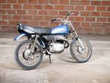 a blue and black motorcycle parked in front of a brick wall