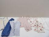 Plusieurs vêtements pour bébés sont disposés sur une table blanche