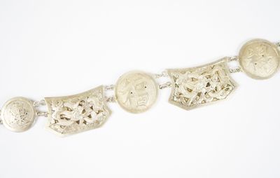 un gros plan d'un bracelet en argent orné de pièces, sur fond blanc