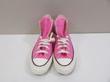 pink converses with white laces are on a white surface