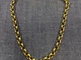 un gros plan d'un collier à chaîne dorée sur fond gris