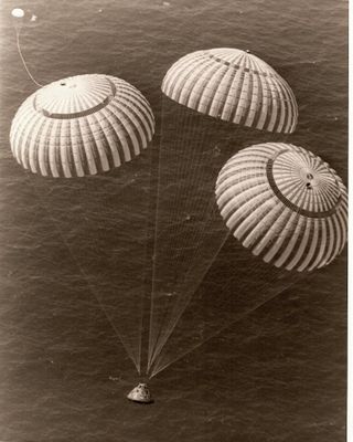 une vieille photo montrant trois parachutes flottant au-dessus de l'océan