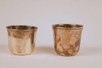 paire de verres à shot anciens en métal argenté sur fond blanc