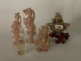 Plusieurs figurines représentant des personnages asiatiques sont exposées sur une surface blanche.