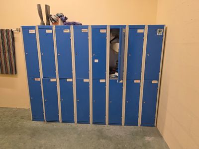 un casier bleu dans une petite pièce où se trouvent de nombreux casiers