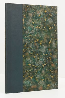 an old book with a green cover sitting on a white surface