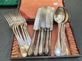 un plateau de couverts posé sur une table où se trouvent d'autres couverts