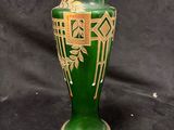 a green vase with gold designs on it on a black background