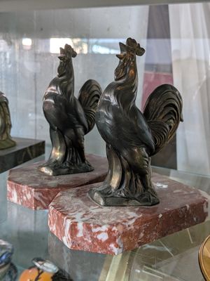 deux statues de coqs exposées dans une vitrine