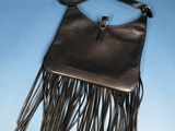 leather purse with fringes hanging on a hanger against a blue background