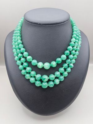 a green beaded necklace on a black mannequin