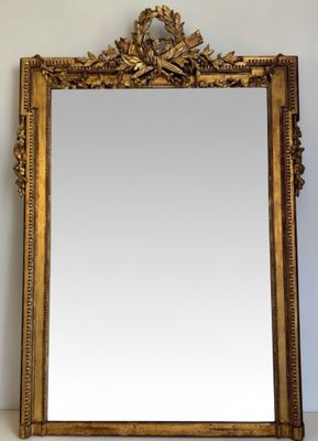 an ornate gold framed mirror on a white wall