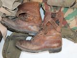 a pair of brown boots sitting on top of a pile of clothing
