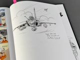 an open book with a drawing of a fighter jet on it