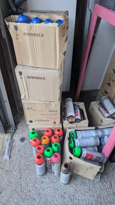 Des cartons contenant des objets divers sont empilés sur le sol devant une porte.
