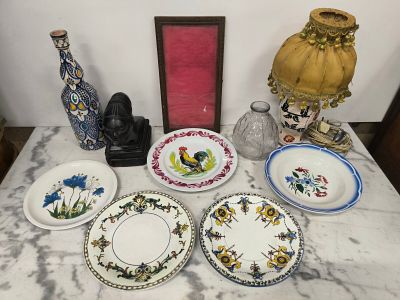 de nombreuses assiettes et vases posés sur une table où se trouve un cadre photo