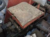 an old tractor with a seat and a seat cushion in a garage