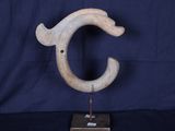 une photo d'une sculpture représentant la lettre « c » posée sur un socle en bois
