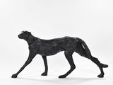 a statue of a dog that is walking on a white surface