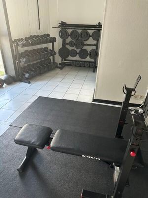 une photo d'une salle de sport avec un banc et des haltères