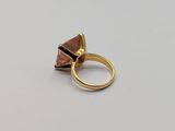 a close up of a gold ring with a pink stone on it