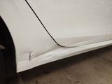 the side of a white car with a dent on it