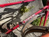 a red bicycle parked next to a stone wall