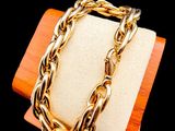 gold plated bracelet on a wooden stand with a black background