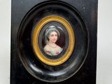 un portrait miniature représentant une femme, dans un cadre noir et doré