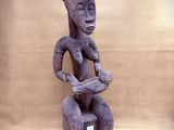 sculpture of a woman sitting on a stool holding a bird