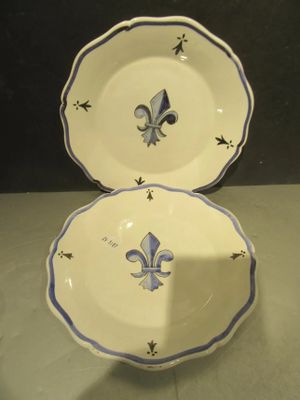 une paire d'assiettes bleues et blanches ornées de motifs de fleurs de lys