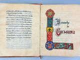 an open book with a decorated letter and a cross on it