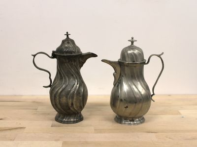 two silver coffee pots sitting on a wooden table