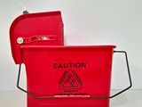 a red mop bucket with a caution sign on it