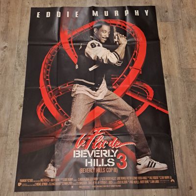 affiche de cinéma représentant un homme sur des montagnes russes, accrochée à un mur en bois