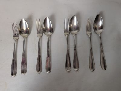 five silver spoons and six silver spoons lined up on a table