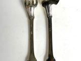 two spoons and a fork on a white table