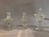 three clear glass vases sitting on top of a white cloth