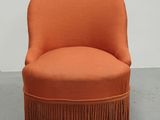 an orange chair with fringes on it in a room