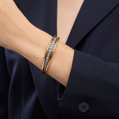 a woman wearing a black blazer and a gold bracelet