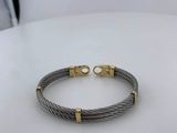 a cable bracelet with two gold clasps on a white table