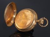 an antique pocket watch on a black surface with a black background