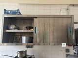 une armoire en acier inoxydable dans une cuisine, avec des casseroles et des poêles posées sur le plan de travail