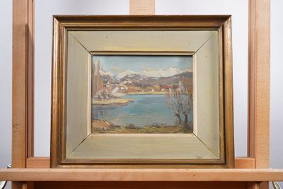 an oil painting of a view of a lake in a frame on a shelf