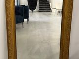 un miroir au cadre doré ouvragé, avec une chaise bleue en arrière-plan