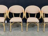 quatre chaises aux sièges rembourrés de couleur beige, placées devant un mur noir