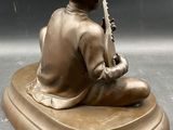 bronze statue of a boy playing a musical instrument on a marble base