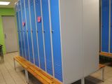 a row of blue lockers in a room with a bench