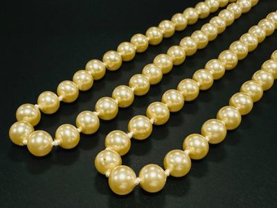 un gros plan sur un collier de perles posé sur une surface noire