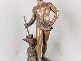 an antique bronze statue of a man with a sword and a hammer